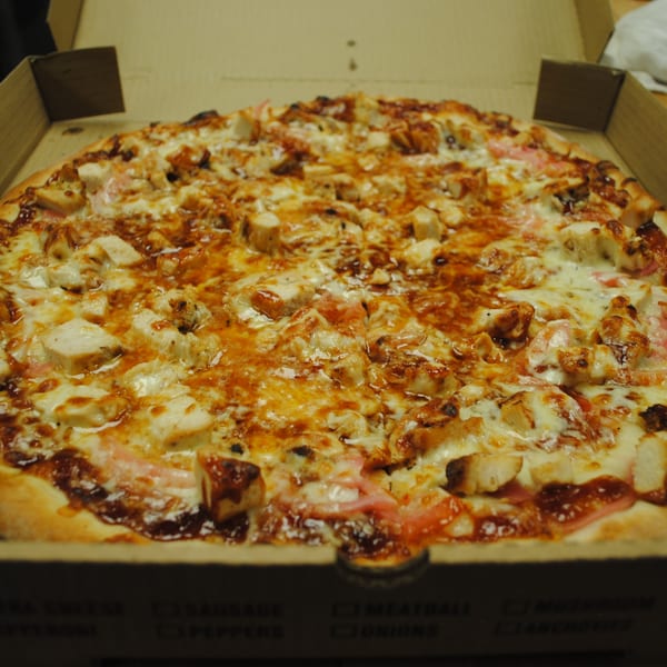 Blue Moon Pizzeria's BBQ chicken pizza, topped with melted cheese and red onions, in a delivery box.