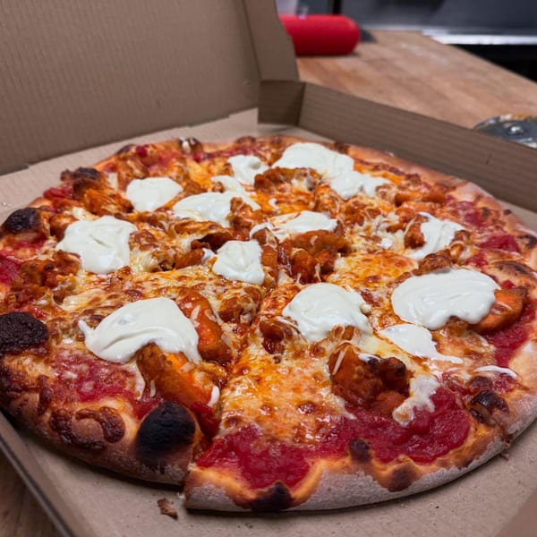Blue Moon Pizzeria's buffalo chicken pizza with white sauce dollops in a cardboard box.