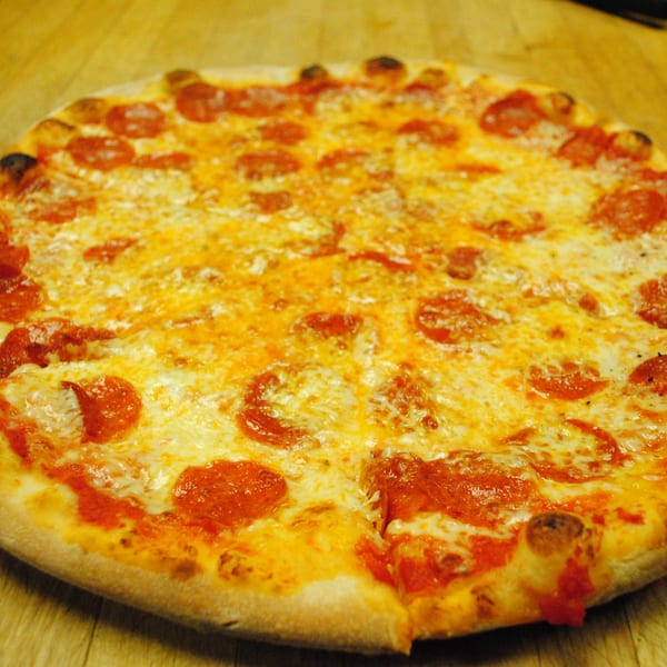 A whole pepperoni pizza from Blue Moon Pizzeria, with one slice slightly pulled away.