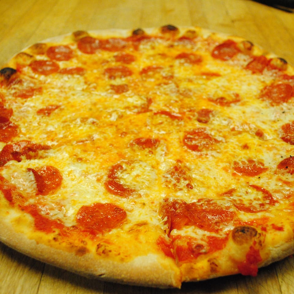 A whole pepperoni pizza from Blue Moon Pizzeria, with one slice slightly pulled away.
